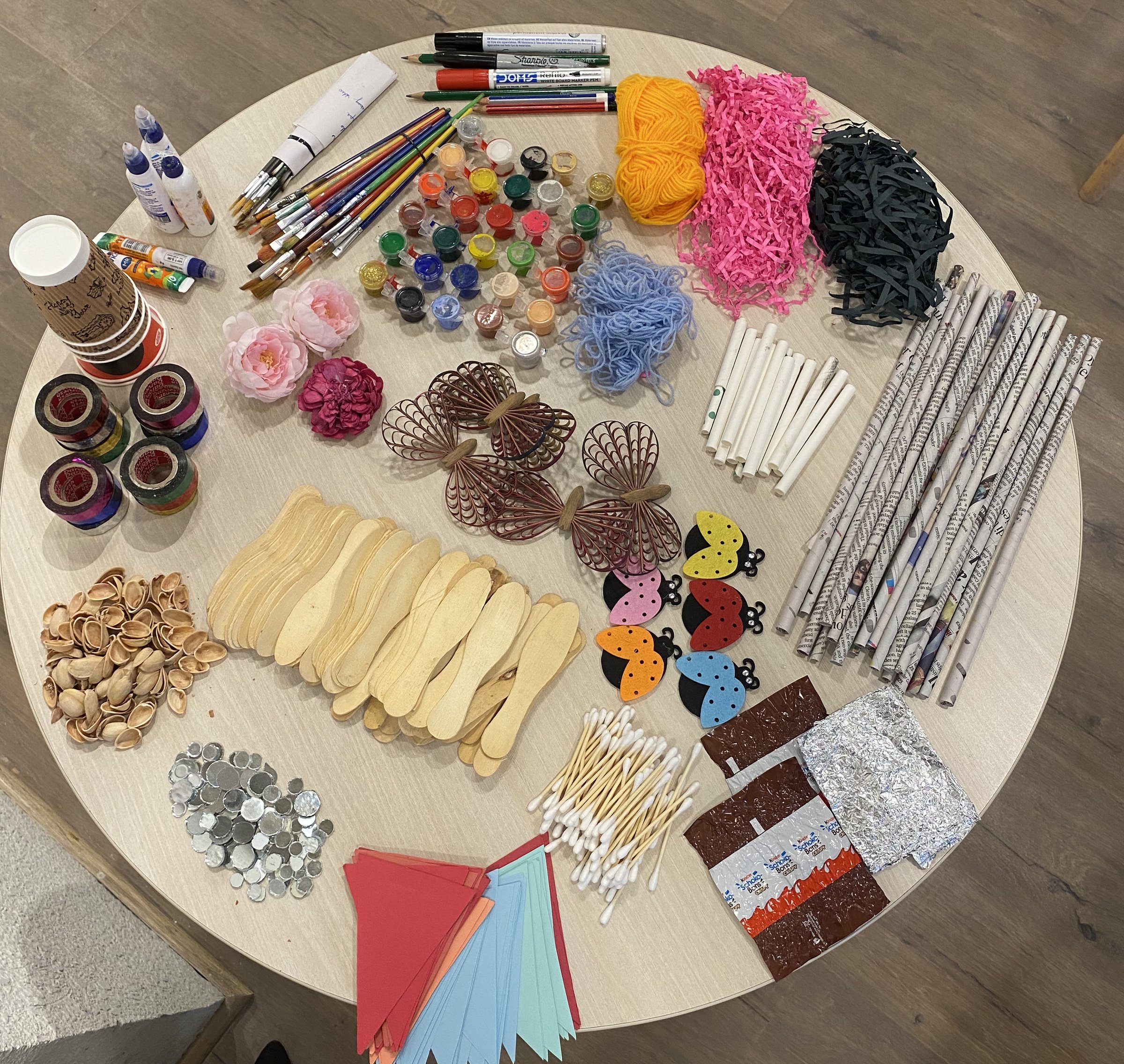 Art materials laid out on a table before a Heart Arts India workshop — brushes, paints, yarn, paper and craft supplies.