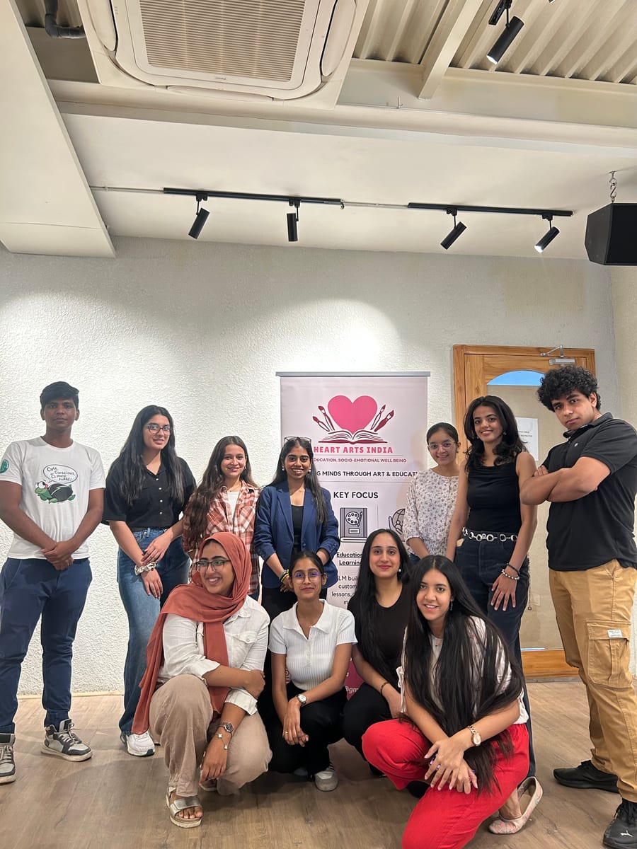 A group of university students gathered around the Heart Arts India banner at the end of a campus session