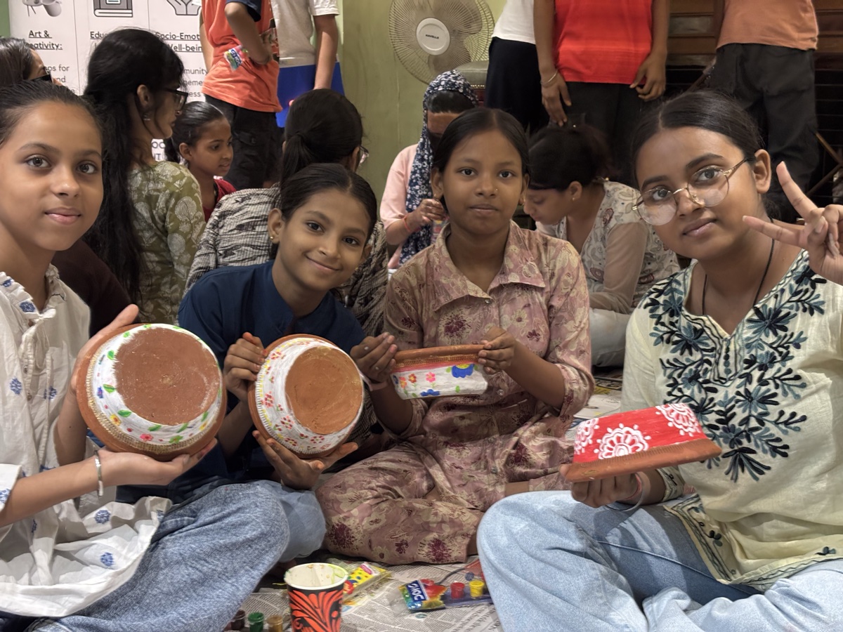 Children holding the terracotta pots they hand-painted in a Heart Arts workshop